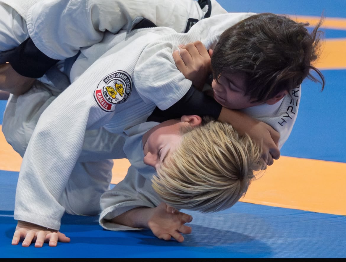 Close view of two youth Jiu Jitsu competitors working from a ground position